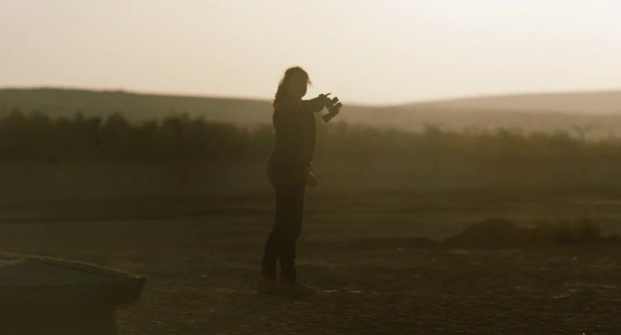 Zero Dark Thirty (2012) movie still: fullbody — A vast, barren desert landscape with rolling hills in the distant background under haze. A woman…