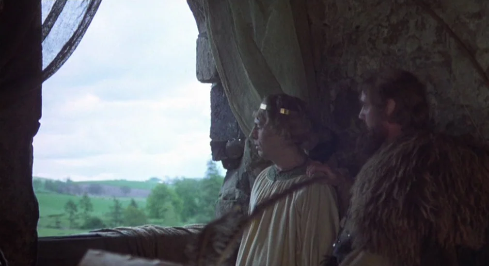 Monty Python and the Holy Grail (1975) movie still: medium — An interior stone chamber with a large arched opening showing a green landscape. Two…