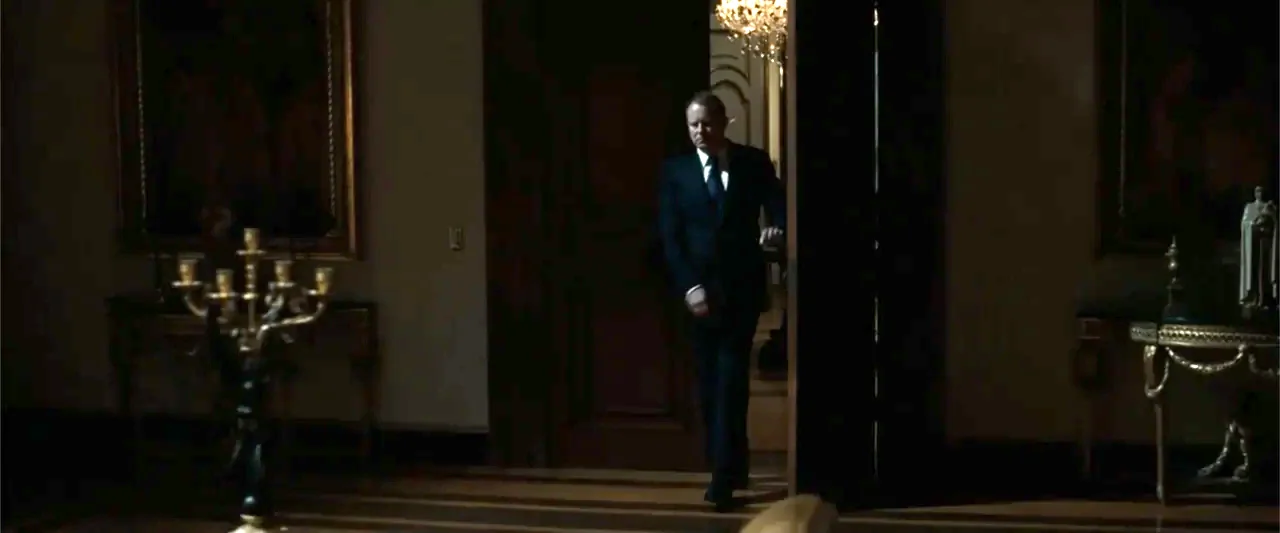Angels & Demons (2009) movie still: fullbody — A dark mansion interior with ornate furniture and large paintings on the walls. A man in a formal…