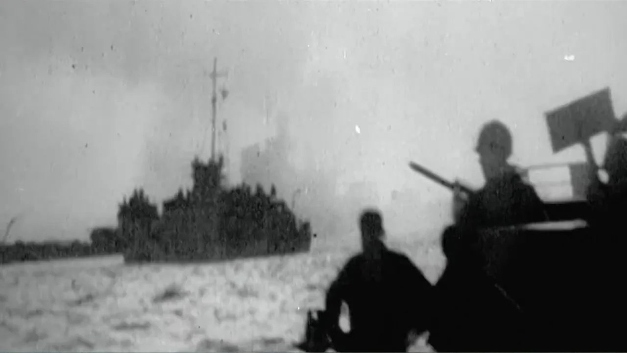 Wartorn: 1861-2010 (2010) movie still: wide — A military landing craft moves across choppy water toward another ship. Two soldiers in silhouette…