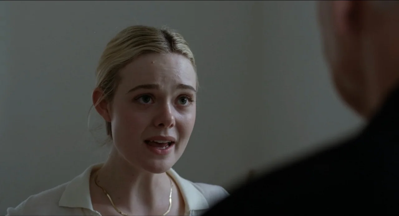 Sentimental Value (2025) movie still: closeup — A spare interior space with plain light gray walls serves as the backdrop. A young woman with blonde…