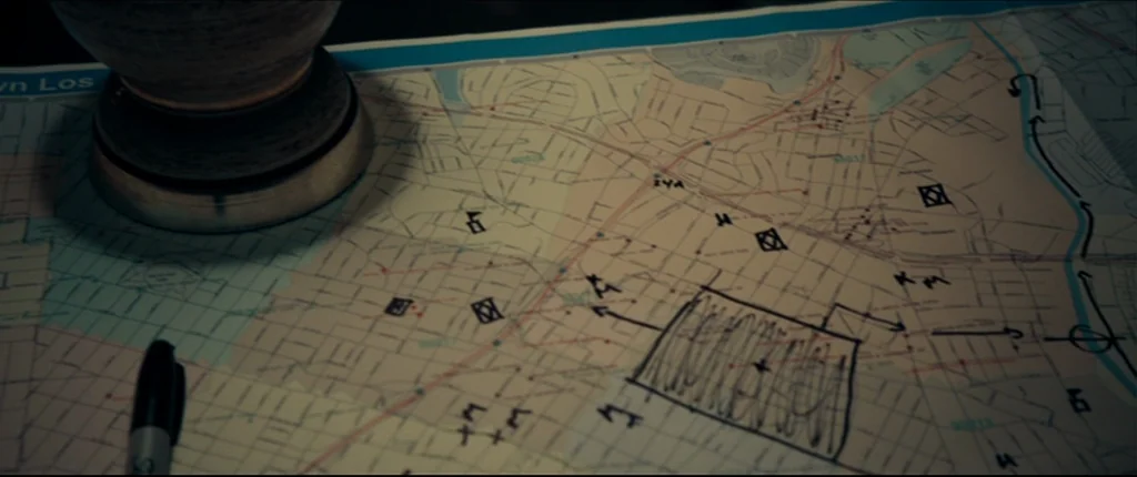 Drive (2011) movie still: closeup — A close-up shot of a city street map laid flat on a table. A dark ceramic vessel and a black felt-tip marker…