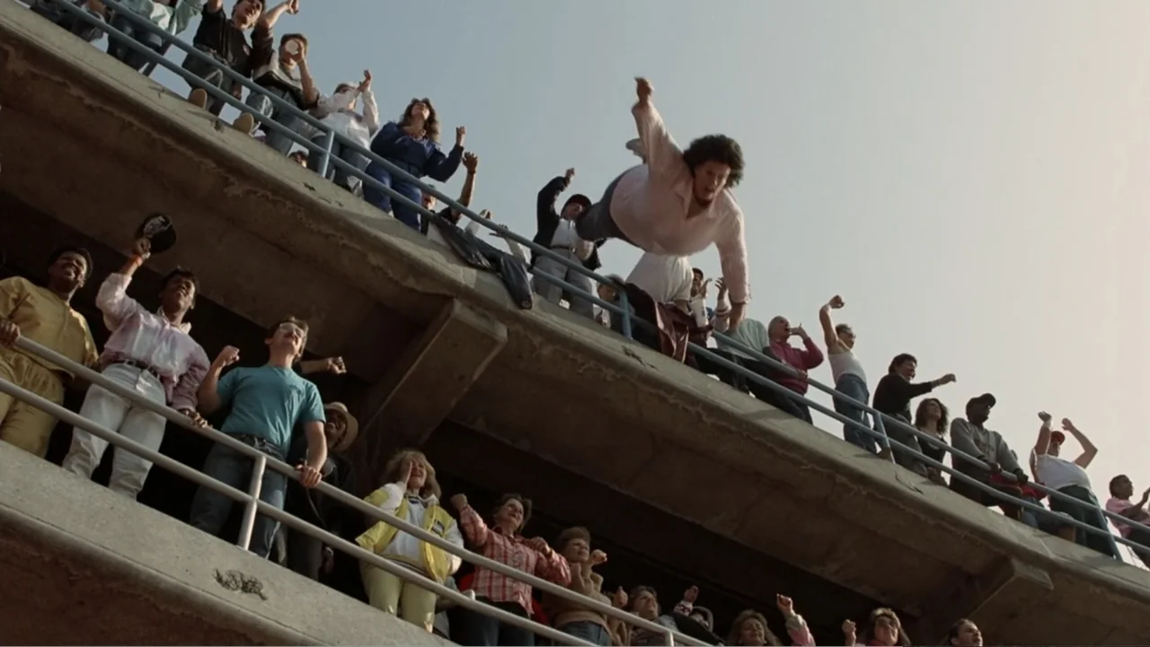 The Naked Gun: From the Files of Police Squad! (1988) movie still: wide — A crowded concrete stadium terrace filled with spectators standing behind…