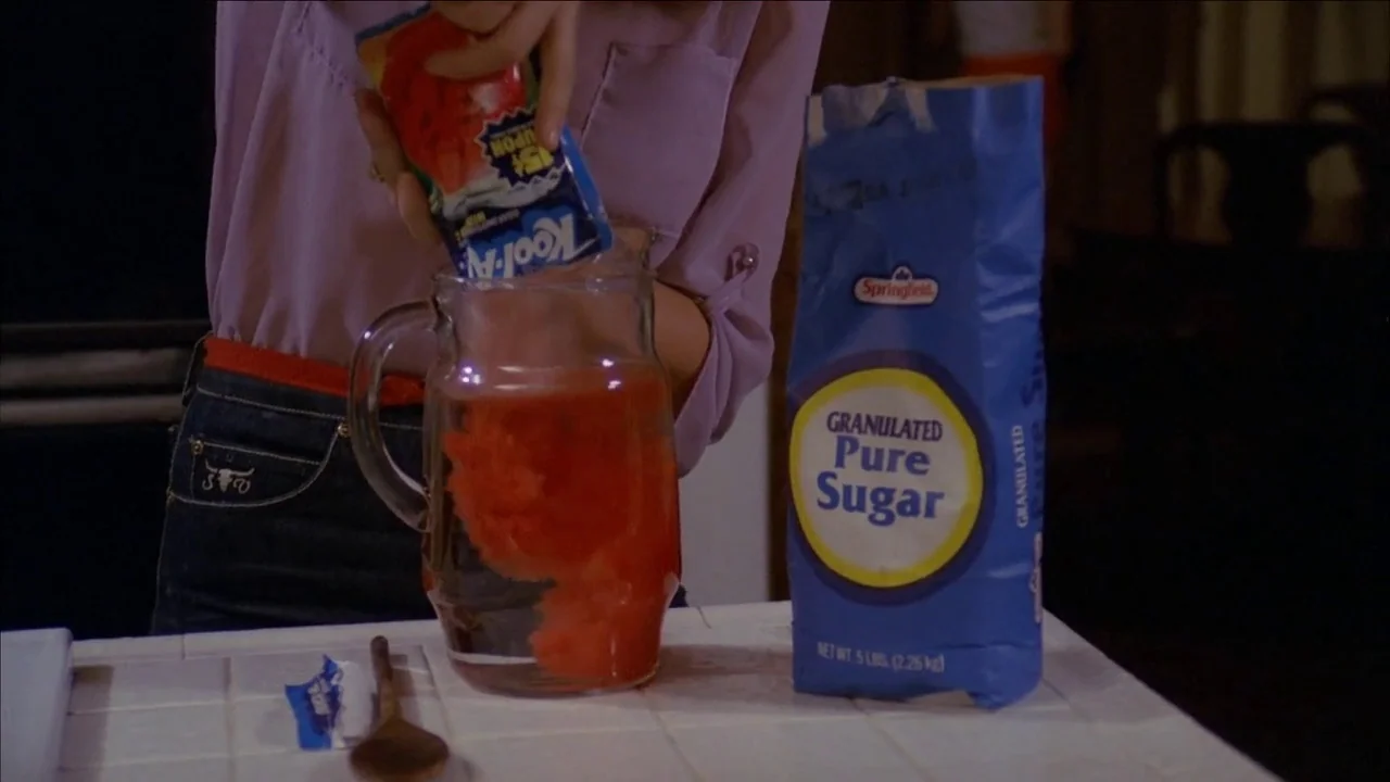 The Slumber Party Massacre (1982) movie still: medium — A person stands at a white tiled counter top in a home environment. The subject pours a…