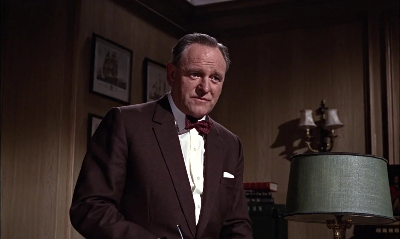 From Russia With Love (1963) movie still: medium — A wood-paneled room features framed nautical prints on the wall and a desk lamp. An older man in…