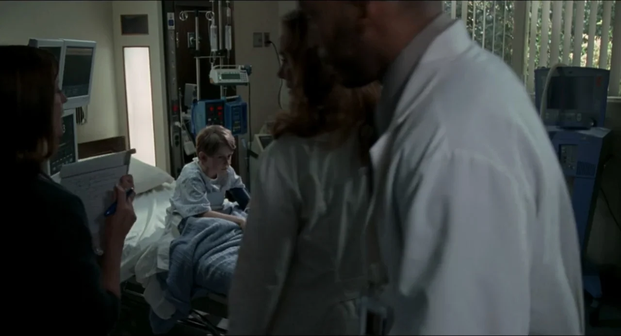 The Ring Two (2005) movie still: medium — A hospital room contains a patient bed with various medical monitoring equipment nearby. A young boy sits…