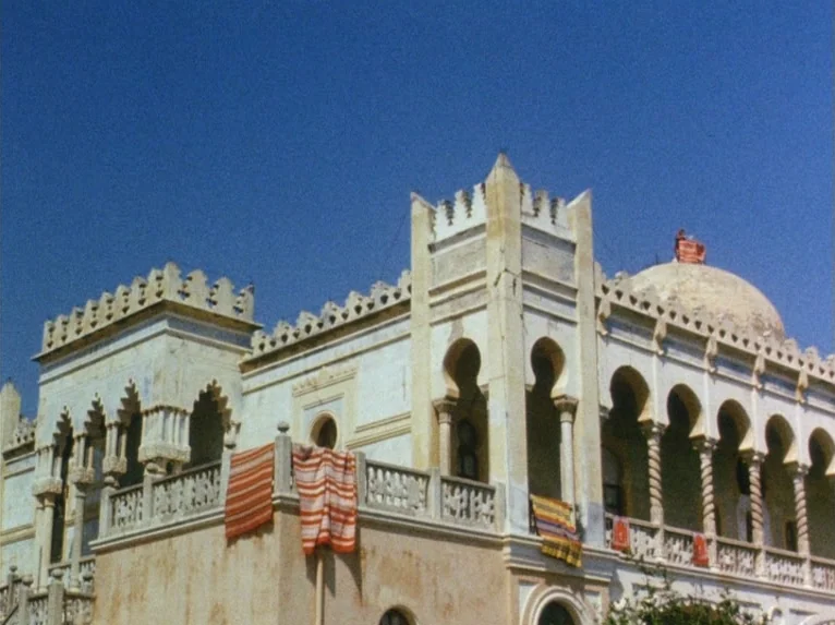 Our Lady of the Turks (1968) movie still: establishing — A light-colored stone mansion features Moorish arches and ornate crenelated battlements.…
