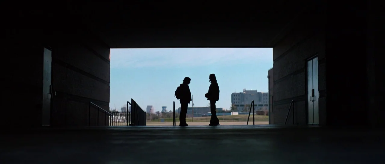 The Boogeyman (2023) movie still: wide — A dark concrete underpass frames an open field with buildings in the background. Two people stand in the…