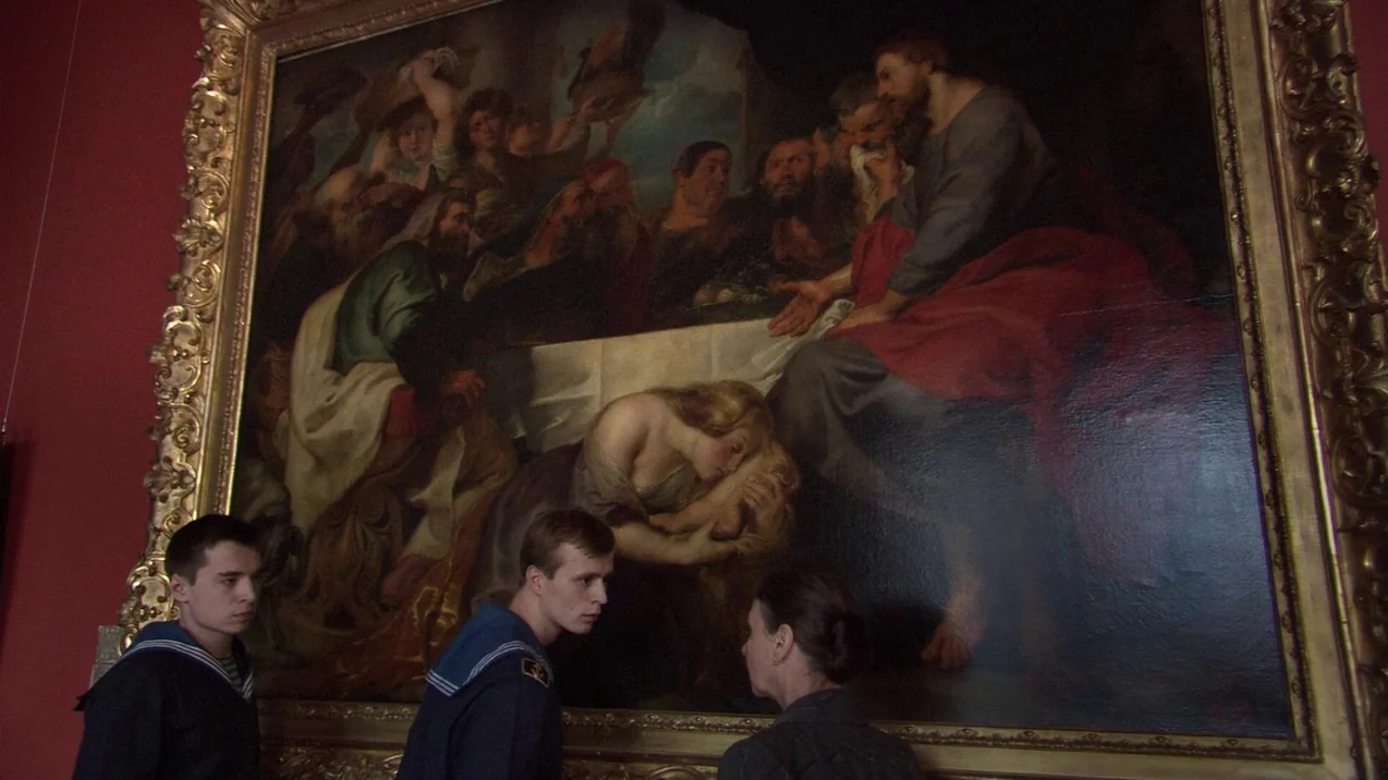 Russian Ark (2002) movie still: medium — A museum gallery features red walls and a large, ornate golden-framed religious oil painting. Two men in…