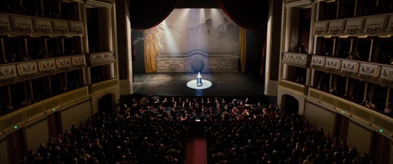 Mission: Impossible – Rogue Nation (2015) movie still: establishing — An opulent opera house filled with an audience features a large stage with…