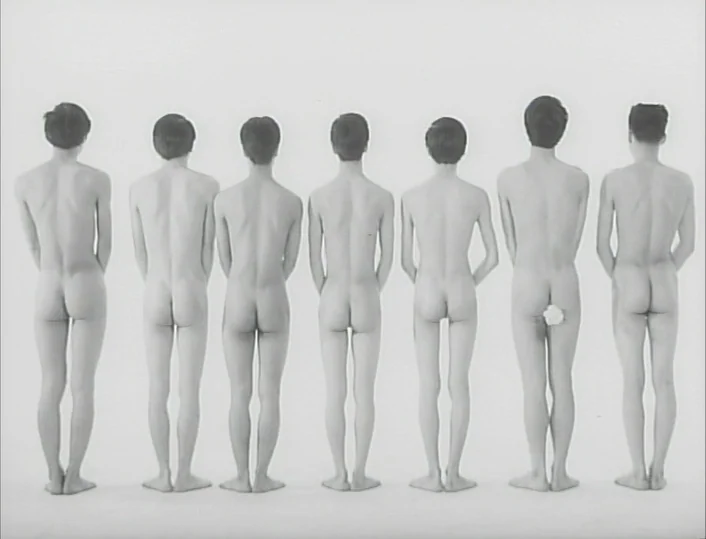 Funeral Parade of Roses (1969) movie still: fullbody — Seven nude men stand in a row against an unadorned, bright white background. They are…