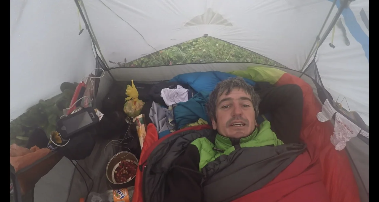 Blutch (2018) movie still: medium — A man lies inside a small, white fabric camping tent filled with scattered outdoor gear. He is resting inside a…