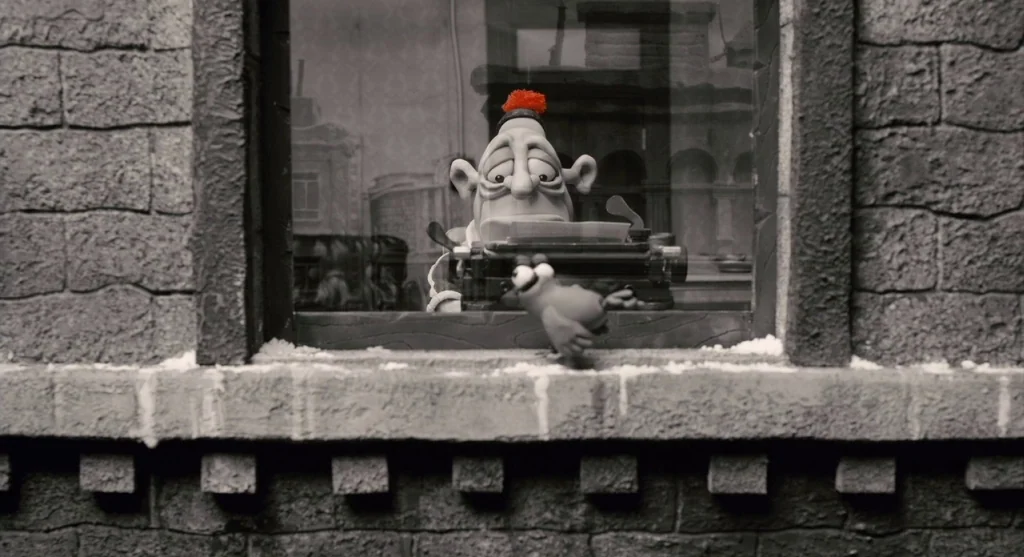 Mary & Max (2009) movie still: medium — A brick building exterior at night features a lone window looking into a workspace. A claymation character…