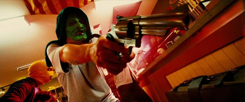 Hobo With A Shotgun (2011) movie still: medium — A video rental store with rows of media shelves bathed in saturated red light. An individual in a…