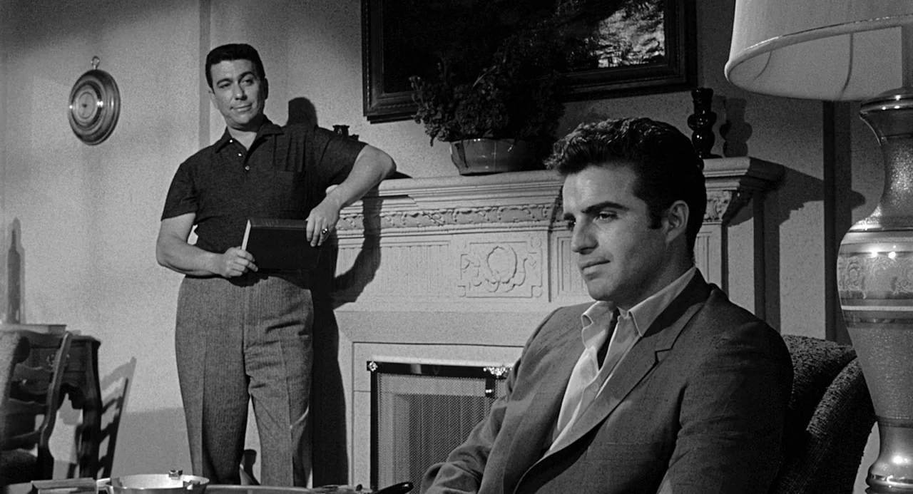 Murder By Contract (1958) movie still: medium — A well-appointed domestic interior features a decorative stone mantle and a wall-mounted barometer.…