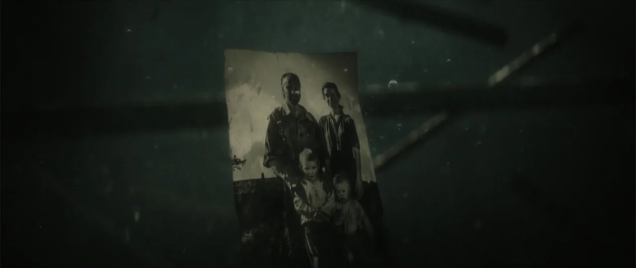 Sisu: Road to Revenge (2025) movie still: closeup — A murky underwater environment contains a floating, water-damaged family photograph. The…