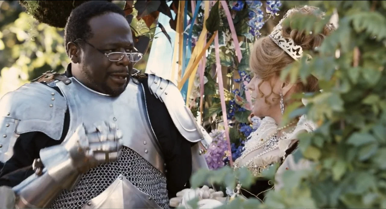 Todo es amor (2024) movie still: medium — A man in medieval armor stands with a woman wearing an ornate dress. They are outdoors amidst hanging…