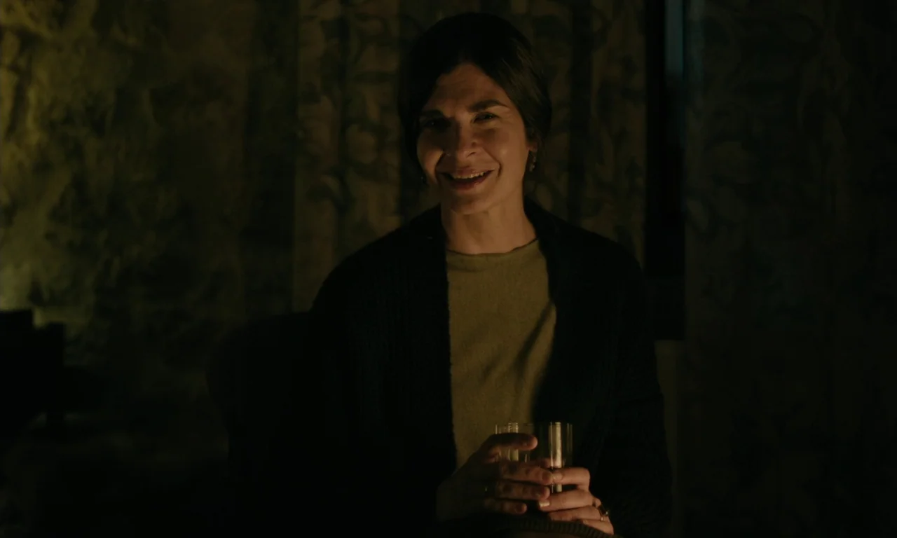 Close Your Eyes (2023) movie still: medium — An interior space features textured stone walls and patterned curtains in dark lighting. A middle-aged…