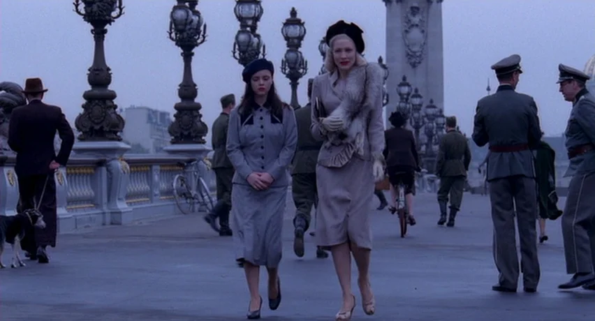 The Man Who Cried (2000) movie still: fullbody — A stone bridge in Paris features elaborate ornate lamp posts and uniformed military personnel. Two…