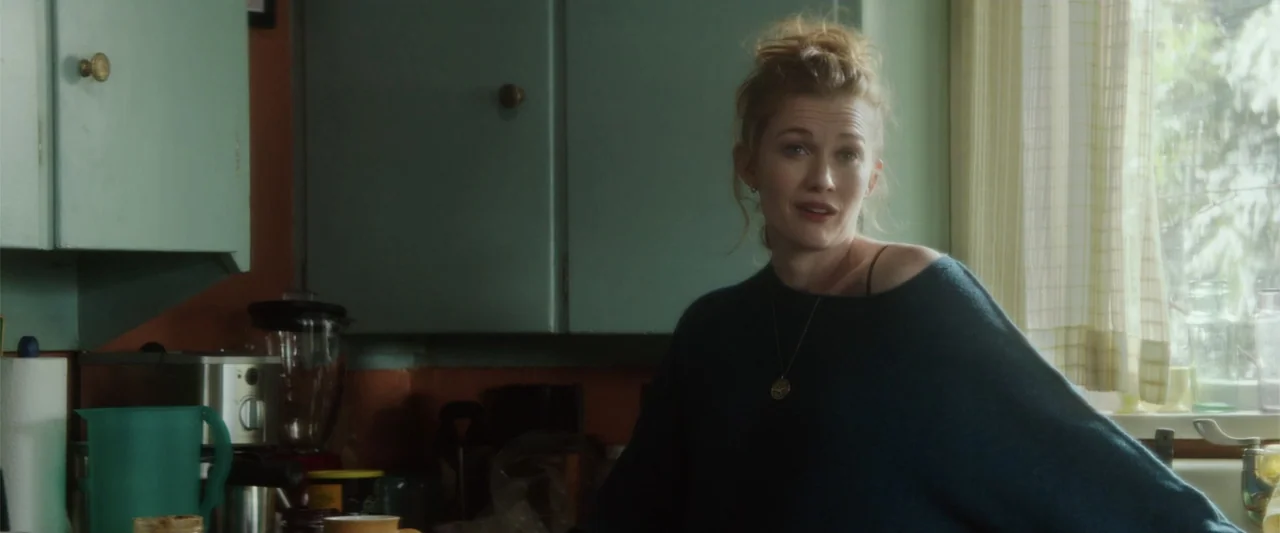 If I Stay (2014) movie still: medium — A residential kitchen features teal-painted wooden cabinets and an orange-toned wall below the cabinetry. A…