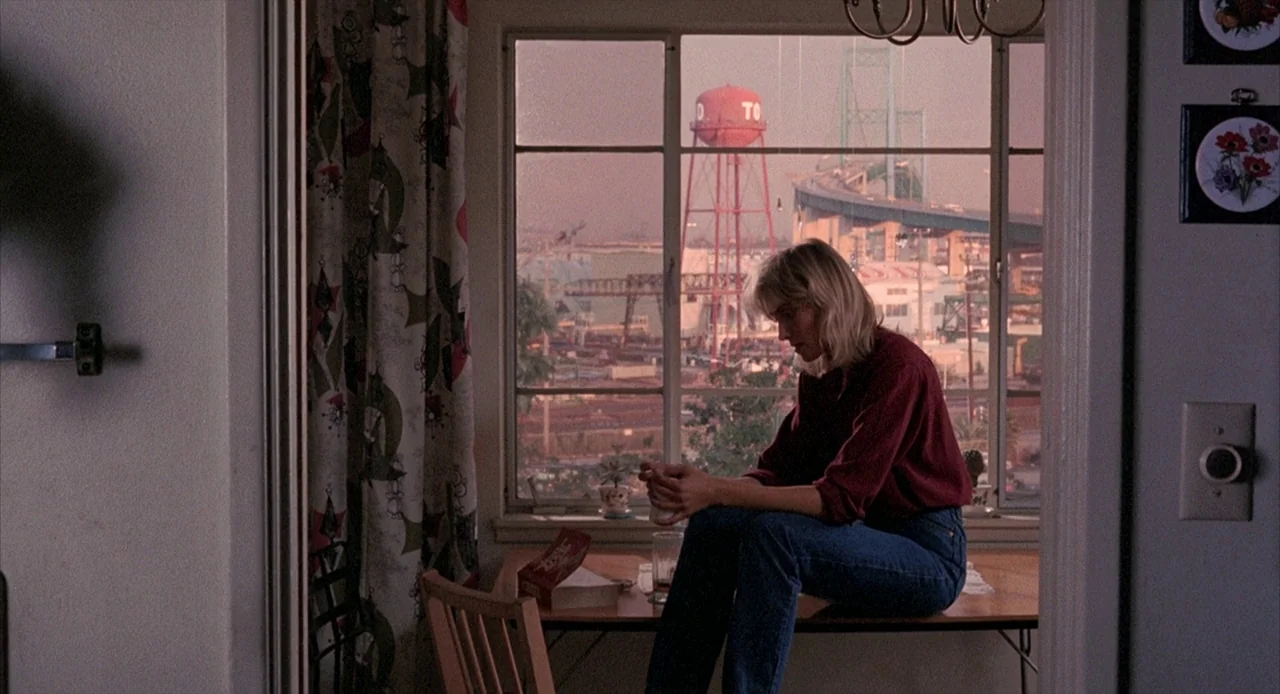 To Live and Die in L.A. (1985) movie still: medium — A residential interior view looking toward a large window overlooking an industrial port…