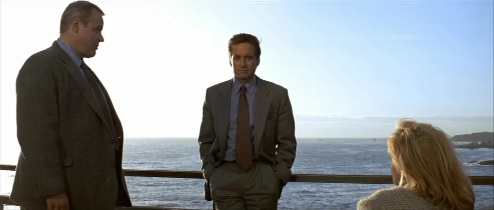 Basic Instinct (1992) movie still: medium — A wooden balcony railing separates three people from the expansive, open ocean at daytime. The…