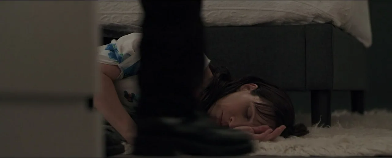 Hostages (2017) movie still: medium — A dimly lit bedroom features a person lying on a textured white rug. Another individual stands directly over…