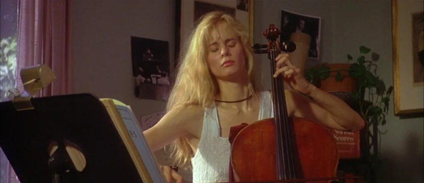 Short Cuts (1993) movie still: medium — An interior space with gray walls decorated with posters and a houseplant. A blonde woman in a white tank…
