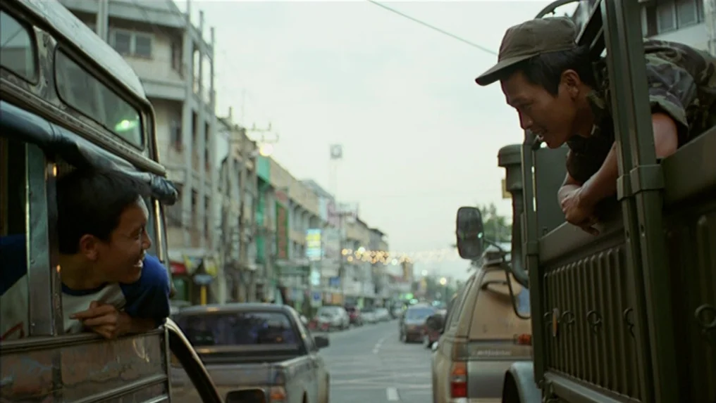 Tropical Malady (2004) movie still: medium — A busy city street with cars and buildings stretches into the distance. Two men in separate vehicles…