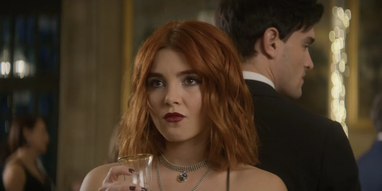 Your Fault (2024) movie still: closeup — A dimly lit indoor event with blurry figures standing in the background. A woman with auburn hair holds a…