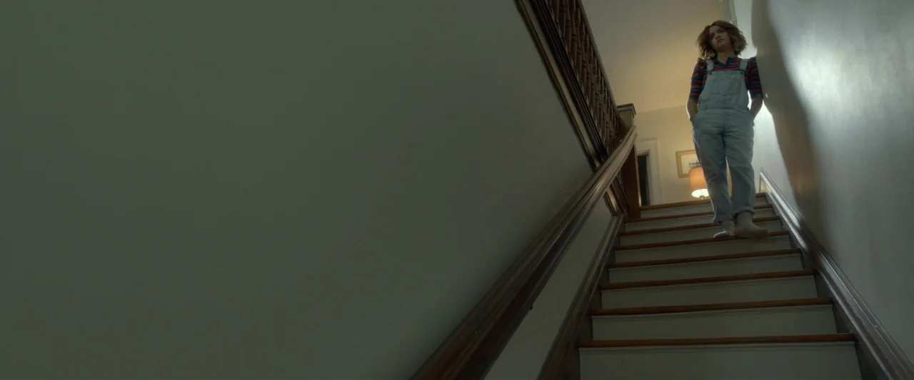 Me and Earl and the Dying Girl (2015) movie still: fullbody — A wooden staircase connects two levels of a residential home with plain grey walls. A…