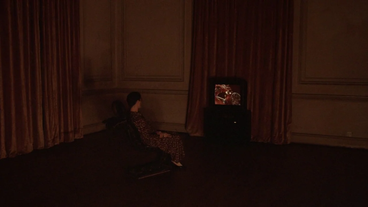 The Lair of the White Worm (1988) movie still: wide — A dark, sparsely furnished room features heavy floor-to-ceiling curtains covering the entire…