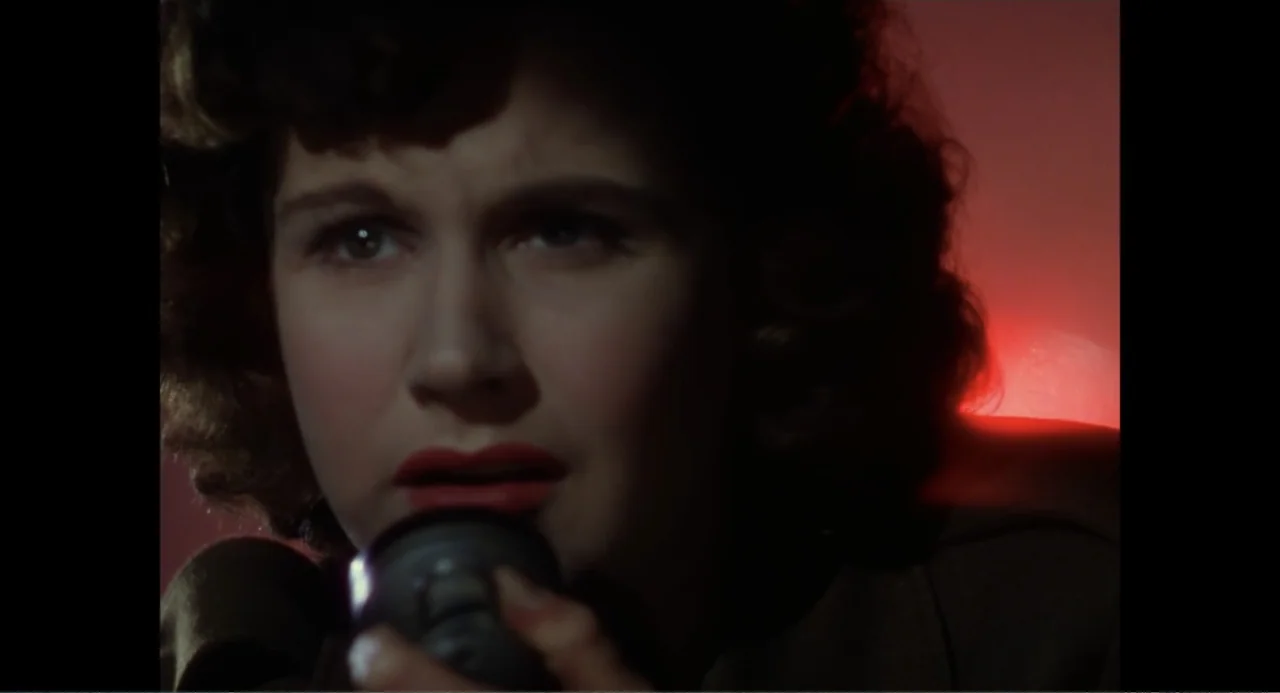 Made in England: The Films of Powell and Pressburger (2024) movie still: closeup — A dark, minimally furnished space is bathed in a distinct crimson…
