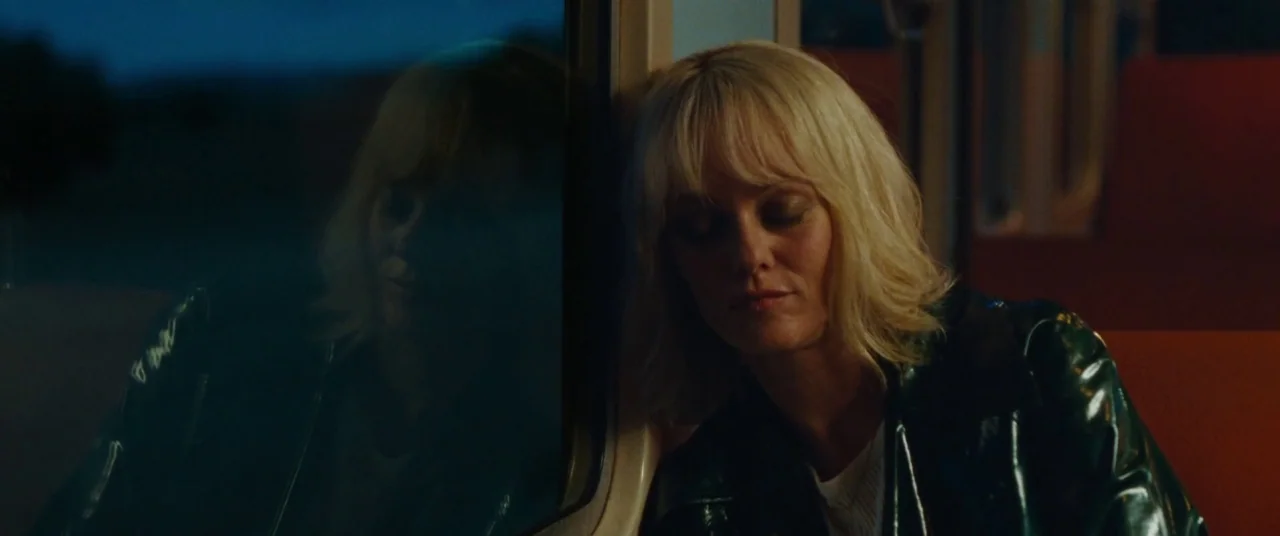 Knife+Heart (2018) movie still: medium — A passenger sits in a dark train carriage during night transit. The woman rests her head against the window…