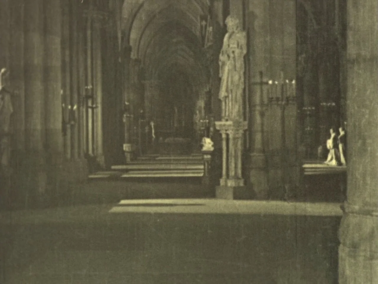 The Hunchback of Notre Dame (1923) movie still: wide — A stone cathedral nave features rows of massive pillars and sculpted statues. Sunlight…