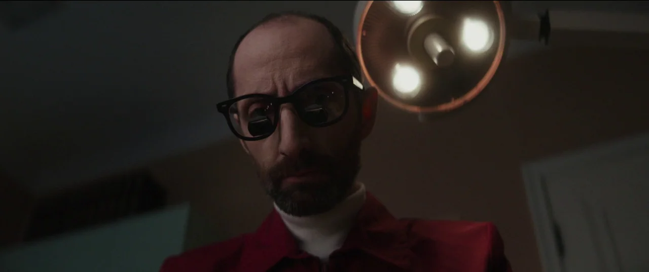 Humanist Vampire Seeking Consenting Suicidal Person (2023) movie still: closeup — A dark medical room with a bright surgical light positioned above…