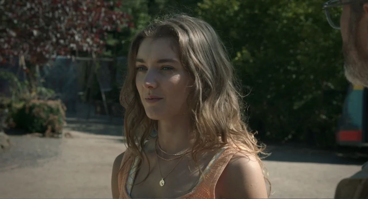 Ice Road: Vengeance (2025) movie still: medium — An outdoor park setting with dense green foliage visible in the soft-focus background. A woman in a…