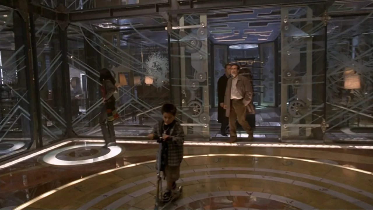 13 Ghosts (1960) movie still: fullbody — A modern lobby features geometric glass partitions and a patterned floor with circular inlays. A young boy…