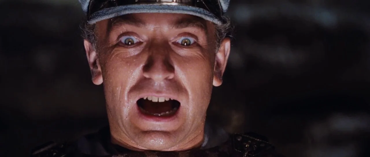 Raiders Of The Lost Ark (1981) movie still: closeup — A dark, undefined interior space serves as the backdrop for a close portrait. The man has…