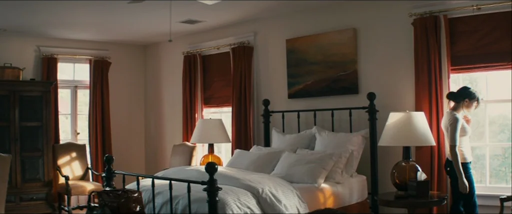 The Girlfriend Experience (2009) movie still: wide — A sunlit bedroom features a black iron bed frame and large windows with red curtains. A young…