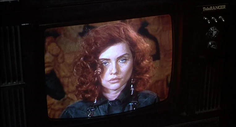 Videodrome (1983) movie still: closeup — A close-up view of a woman on the screen of a TeleRanger television set. The woman has wavy red hair and…