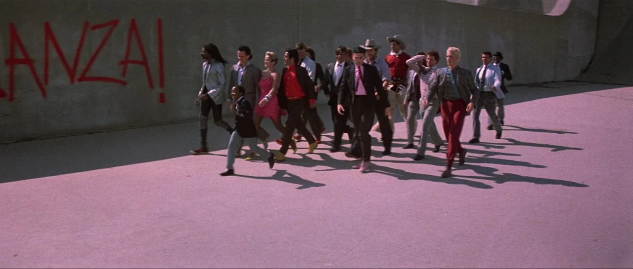 The Adventures of Buckaroo Banzai Across the 8th Dimension (1984) movie still: wide — A group of people walks across a large, empty concrete flood…