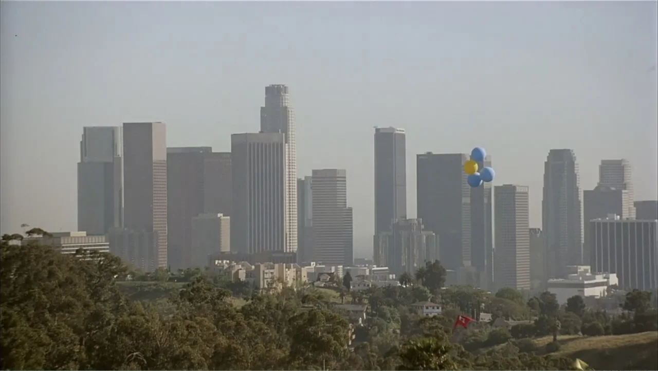 Ajuste de Cuentas (2016) movie still: establishing — A hazy view of the Los Angeles skyline features numerous office towers and skyscrapers. A small…
