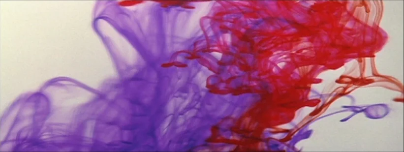 Kwaidan (1964) movie still: closeup — Red and purple ink plumes swirl through a transparent aqueous environment against white. The concentrated dyes…