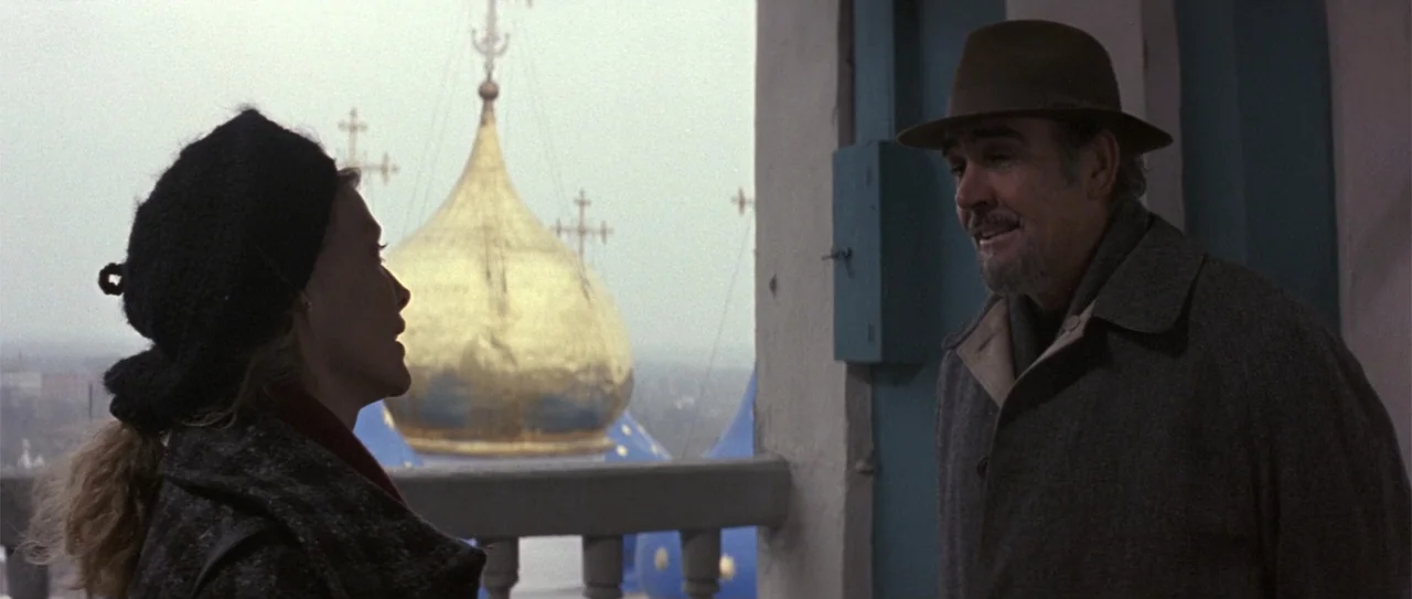 The Russia House (1990) movie still: medium — An outdoor balcony overlooks a landscape featuring an onion-domed church with a gold roof. An older…