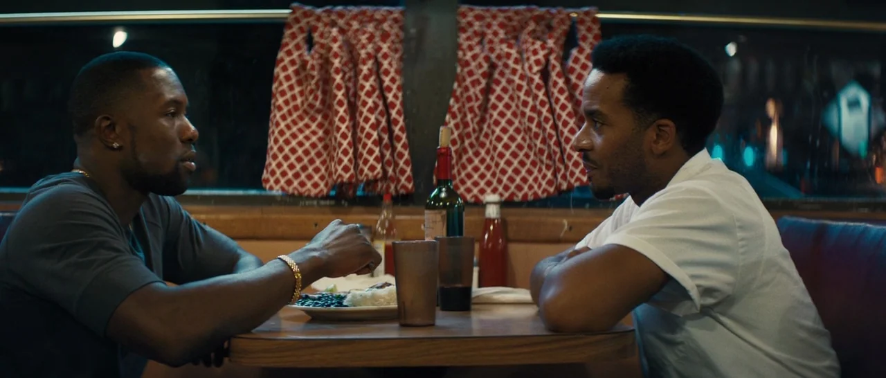 Moonlight (2016) movie still: medium — Two men sit across from each other at a small table inside a dimly lit diner. A bottle of red wine and food…