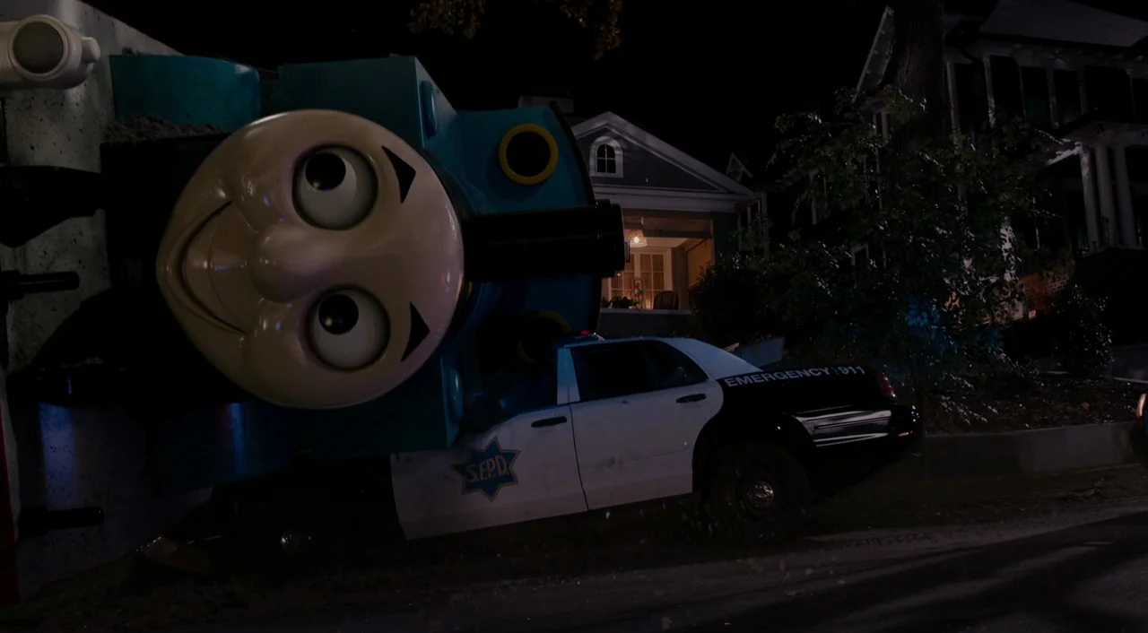 Ant-Man (2015) movie still: wide — A dark residential street features a giant Thomas the Tank Engine toy train tipped over. The train rests directly…