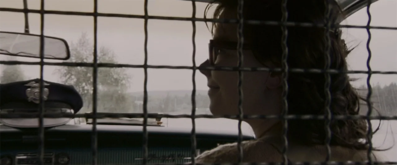 Dancer in the Dark (2000) movie still: medium — The interior of a moving police car features a metal security grate separating the seats. A young…