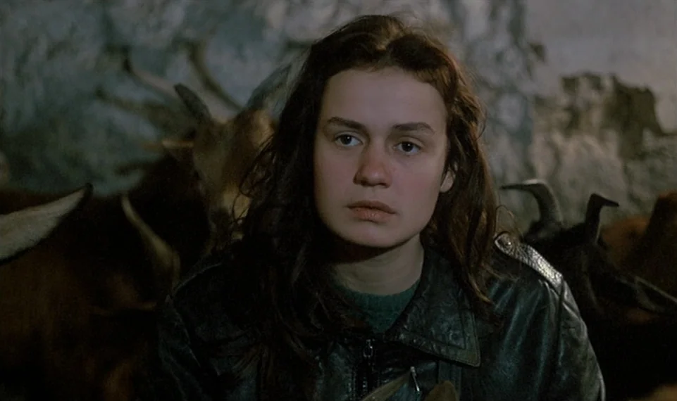 Vagabond (1985) movie still: medium — A dimly lit indoor space with textured, weathered walls behind the subject. A young woman in a leather jacket…