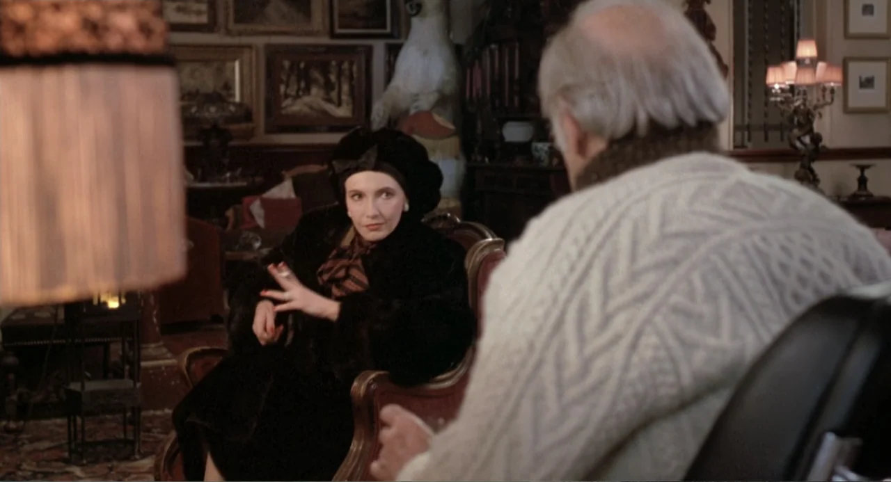 Dead of Winter (2025) movie still: medium — A wood-paneled room is filled with framed artwork and a stuffed polar bear mount. A woman in a black fur…